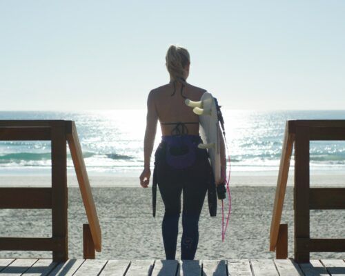 woman-with-surfboard-on-wooden-deck